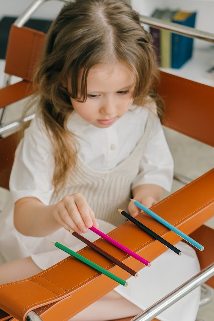 Young girl concentrating on arranging colored pencils creatively indoors.